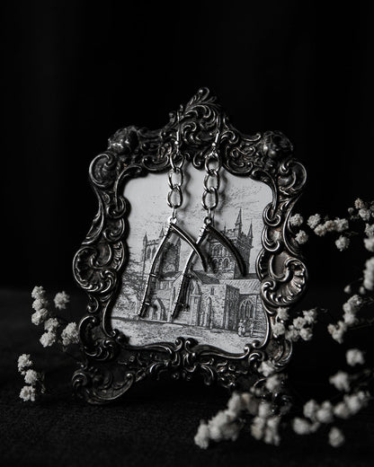 Vista de los Scythe Earrings de The Pretty Cult con diseño de guadaña plateada